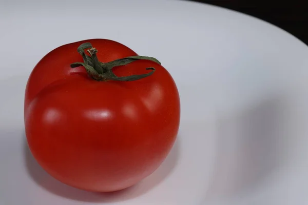 还活着的食物 一个成熟的大番茄躺在桌子上的白色服务盘与黑暗的背景 — 图库照片