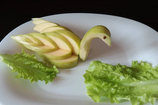 Kuğu ayarlama tablo yeşil elma oyulmuş ve plaka karanlık bir arka plan üzerinde hizmet veren bir beyaz üzerine koydu.