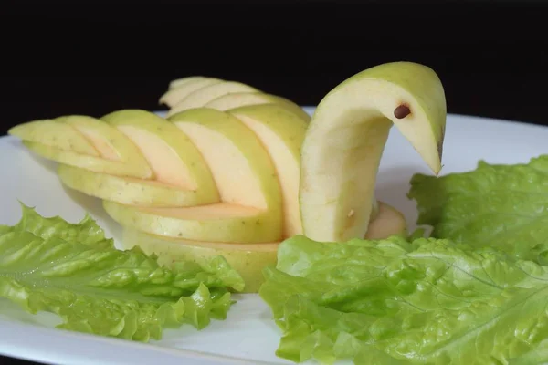 Kuğu ayarlama tablo yeşil elma oyulmuş ve plaka karanlık bir arka plan üzerinde hizmet veren bir beyaz üzerine koydu.