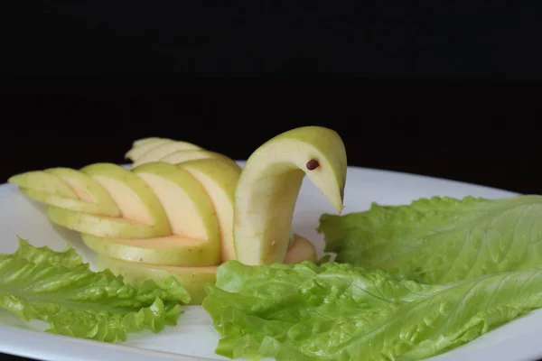Kuğu ayarlama tablo yeşil elma oyulmuş ve plaka karanlık bir arka plan üzerinde hizmet veren bir beyaz üzerine koydu.