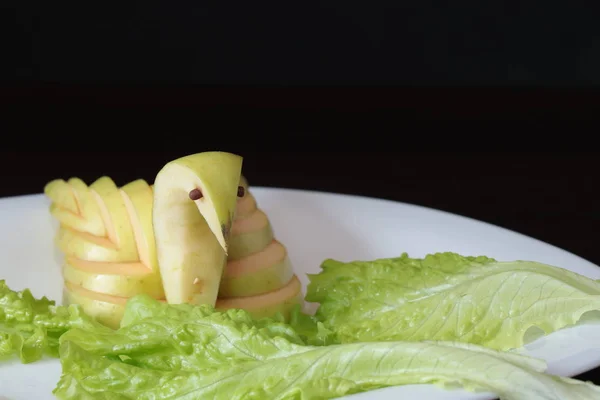 Kuğu ayarlama tablo yeşil elma oyulmuş ve plaka karanlık bir arka plan üzerinde hizmet veren bir beyaz üzerine koydu.