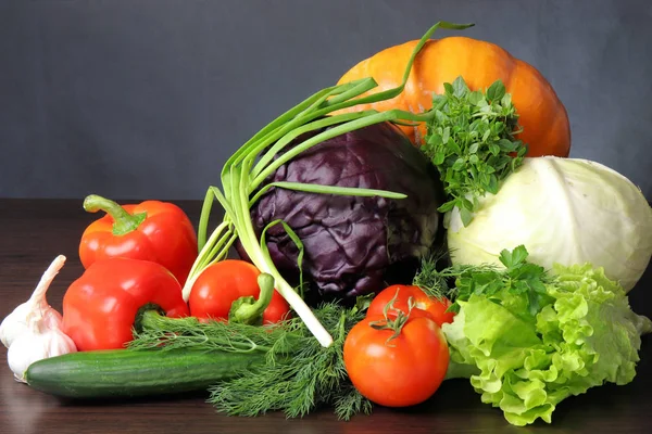 Karanlık bir arka plan üzerinde sebze natürmort. Görüntü sebze. Arka taraf kırmızı lahana ve Beyaz lahana büyük portakal kabak, önünde büyük bir kırmızı tatlı biber kırmızı domates ve salatalık gibi maydanoz ile vardır. 