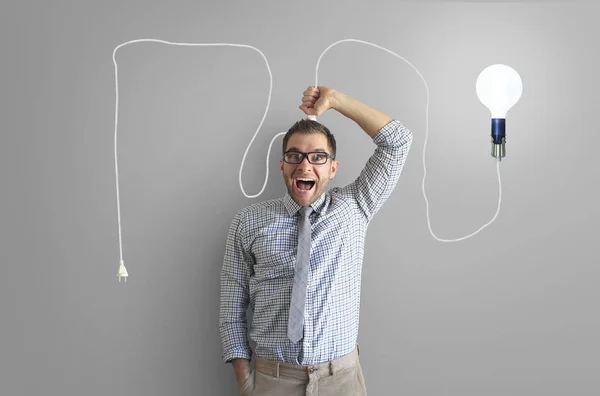 Young man smiles and holds a bright light bulb on the wire