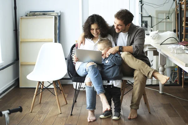 Young family with laptop in bright room at home