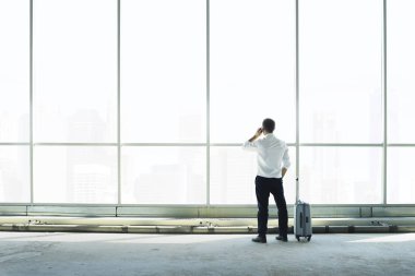 İşadamı büyük bir pencereye karşı telefonda konuşuyor