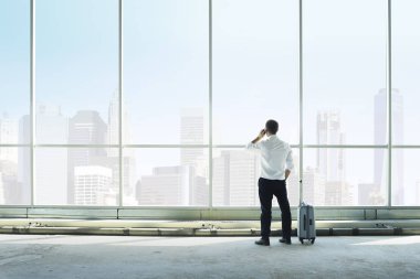 İşadamı büyük bir pencereye karşı telefonda konuşuyor