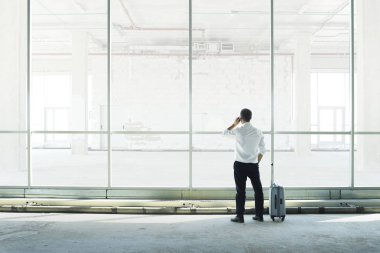 İşadamı büyük bir pencereye karşı telefonda konuşuyor