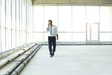 Genç işadamı büyük salonda telefonla konuşuyor.