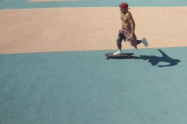 Genç bir adam paten parkında kaykay sürüyor.