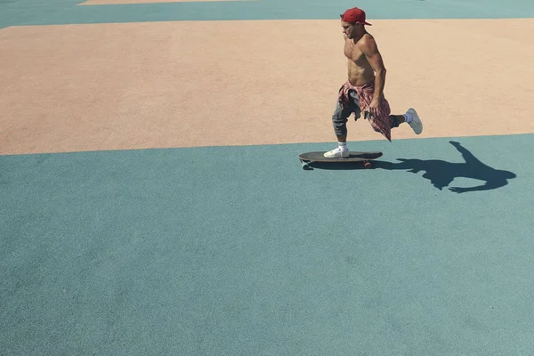 Genç bir adam paten parkında kaykay sürüyor.