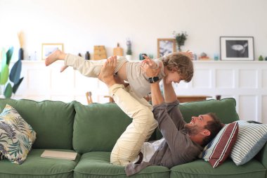 Baba ve küçük oğlu kanepede oynuyorlar.