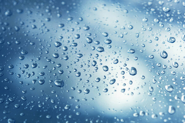 Real water drops on blue gradation background, close up. Raindrops on the window glass. Condensation