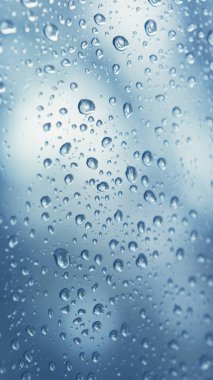 mavi arka plan üzerinde su damlaları, yakın çekim. Pencere camına yağmur damlaları