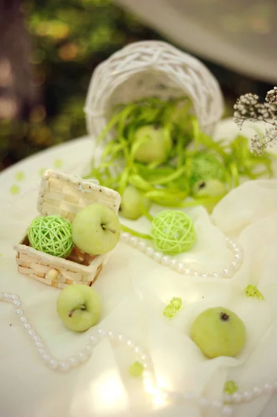 beautiful decoration with green stuff, apples and pearls on table, wedding ceremony
