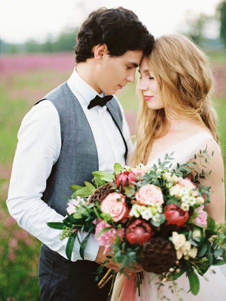 outdoor portrait of happy newlyweds, smiling bride holding beautiful bouquet