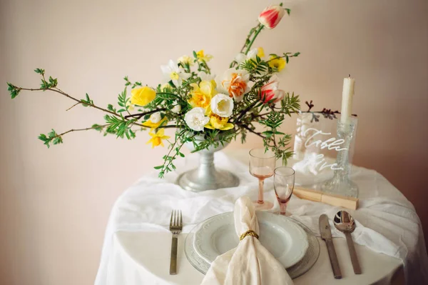 お祝いのテーブルの上の皿 使い捨てからす花瓶の春の花の花束 — ストック写真