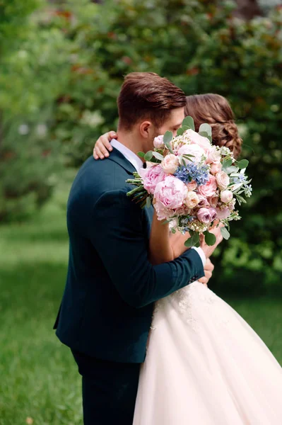 婚礼情侣在绿色公园接吻 美丽的婚礼花束与白色 粉红色 蓝色玫瑰 快乐的新娘和新郎夏季婚礼 — 图库照片