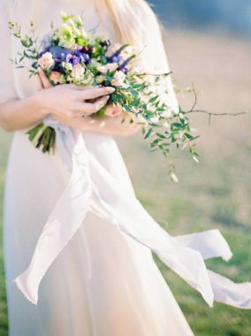 bahar çim üzerinde yürüyüş beyaz gelinlik Genç gelin ve zarif çiçek buket tutarak 