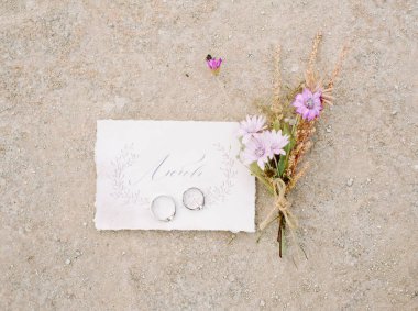 Altın alyans, düğün kartı ve pembe çiçekler, sonsuz aşk kavramı 