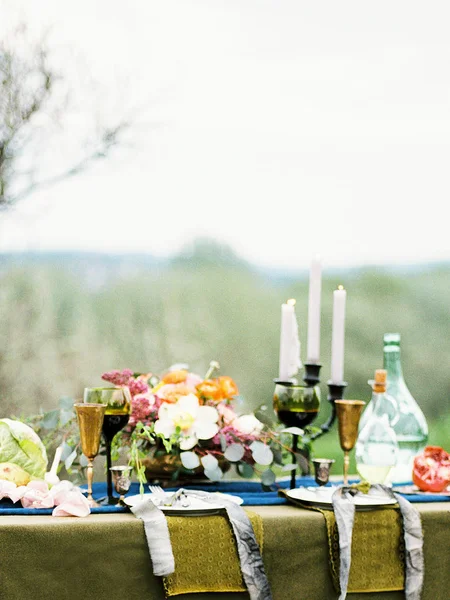 elegant bouquet, candles and food on table outdoor