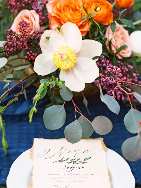 木製のテーブル プレートとカトラリーのメニューカードにエキゾチックな花と明るいカラフルな花束 ディープブルー オレンジ イエロー ホワイト グリーン グレー バラ色 — ストック写真
