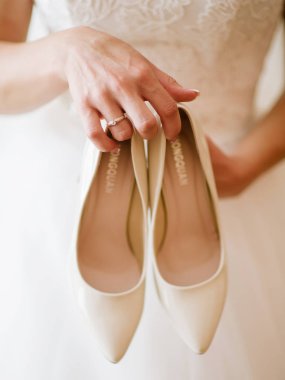  beyaz gelinlik ve pembe ayakkabı tutan gelin 