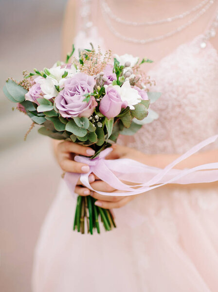 bride in white dress holding wedding bouquet with tender flowers