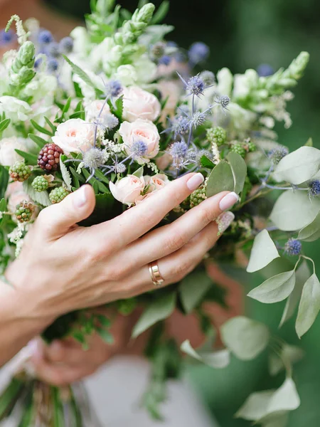 female hand holding elegant wedding bouquet with tender flowers