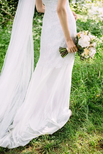 公園で屋外結婚式 長い電車の歩行と柔らかい牡丹の花と結婚式の花束を保持して白いレースのドレスで花嫁 緑の草の背景 — ストック写真