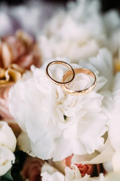 Golden wedding rings and white flowers, eternal love concept