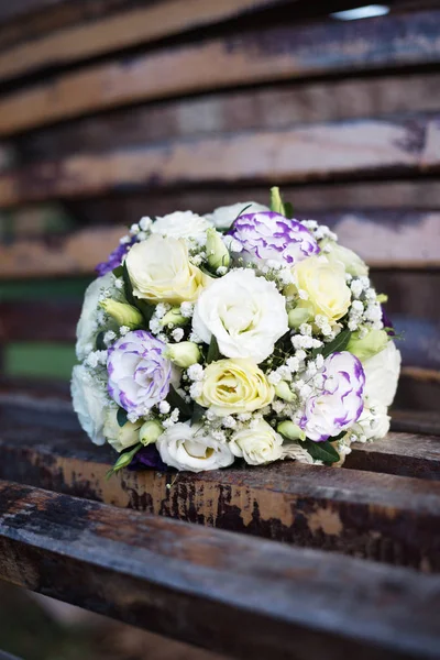 Geleneksel yuvarlak gül buketi ve kahverengi bankta yumuşacık çiçekler..