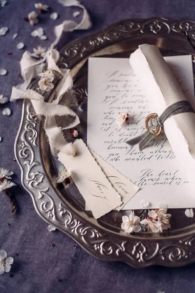 Aşk mektubu. Eski tarz mesaj, kurdeleli klasik kağıt rulo, balmumu damga ve gümüş tepside çiçek yaprakları. Davetiye kartı