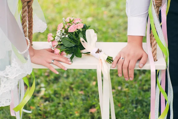 夏の結婚式の概念 緑の背景に結婚式の花束と新郎新婦の手 ブライダルベールとホワイトスイング — ストック写真