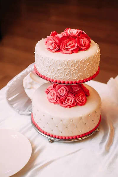 White wedding cake decorated with red roses flowers. Classic pink wedding inspiration