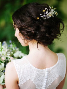 Şık bir düğün saçı. Beyaz dantelli gelinlik, büyük boy buket ve dikiz manzaralı gelin portresi. Yeşil bahçede yaz düğünü..