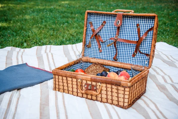Keranjang piknik dengan buah-buahan di latar belakang rumput — Stok Foto