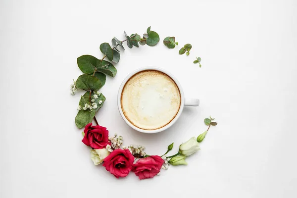 Cappuccino ve çiçek kompozisyon. Beyaz kahve fincanı kremli köpük, taze çiçekler daire beyaz, üst kısmında görüntüleyin. Sıcak içecekler, mevsimlik teklif kavramı