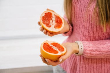 Kadının kesme taze greyfurt mutfak üzerinde eller. Kız kesme bıçağı portakallı. Sağlıklı yaşam konsepti.