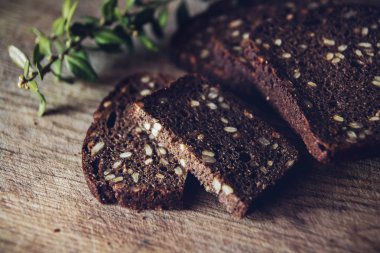 Dilimlenmiş kahverengi ekmek kesme tahtası üzerinde siyah arka plan ile ahşap masa, yakın çekim.