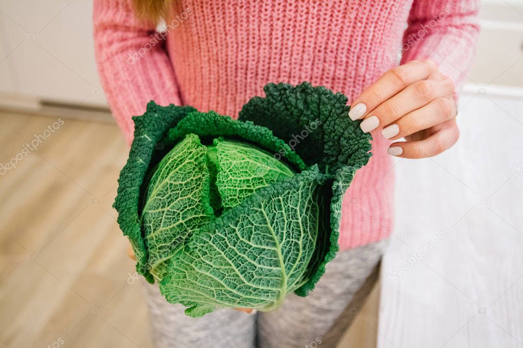 The girl keeps the cabbage. Young woman with cabbage. Cabbage in the hands