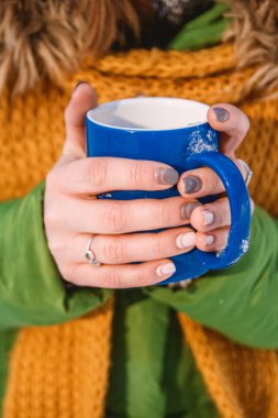 Elinde bir fincan sıcak kahve tutan bir kadının yakın çekimi.