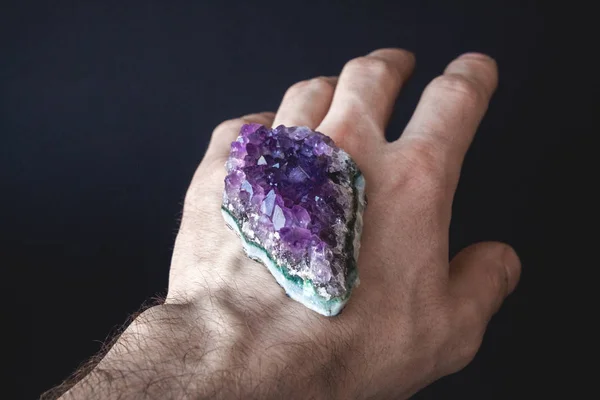 Druso di cristalli viola naturali non trattati di ametista su un pezzo di roccia si trova sul palmo della mano — Foto Stock