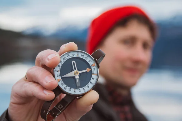 Traveler man houdt een oude kompas tegen de achtergrond van de berg en een meer. Het concept van het vinden van jezelf de weg en de waarheid. Een kijkje op de camera. — Stockfoto