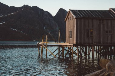 Dağların arka planına karşı gölün yanında eski ahşap balıkçı evleri. Norveç, Avrupa. Kopya alanı. Banner olarak kullanabilirsiniz