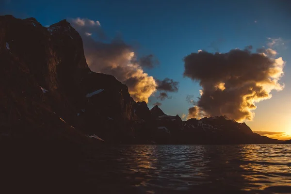Zachód słońca nad górami nad morzem. Sylwetka gór. Piękne chmury — Zdjęcie stockowe