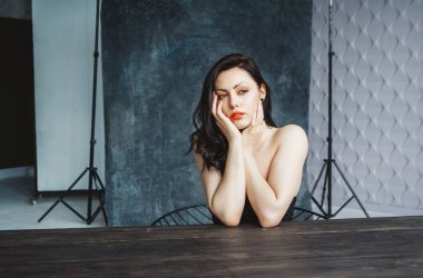 Koyu gri fotokopi arka planında oturan güzel esmer kadının portresi. Güzel elbiseli, güzel, doğal bir kız.