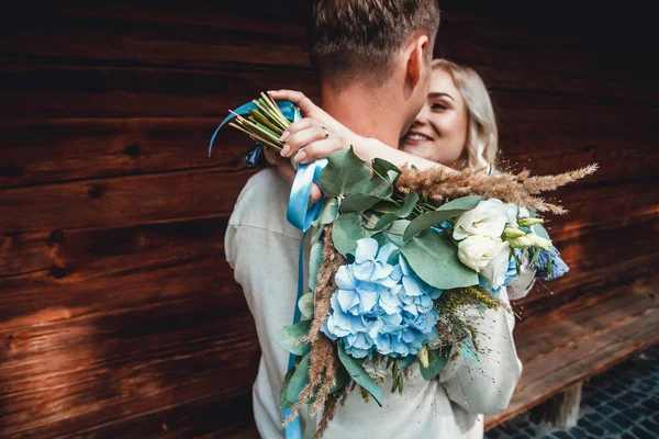 Casal incrível em uma camisa de bordados com um monte de flores no fundo de uma casa de madeira Fotos De Bancos De Imagens