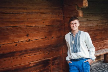 Ahşap bir evin arka planında işlemeli gömlek güzel genç adam