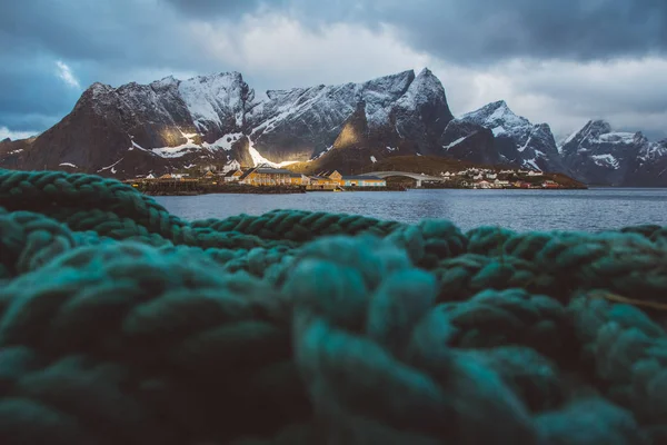 Norveç rorbu evleri ve fiyort manzara İskandinav seyahat görünümü Lofoten adaları üzerinde kayalar dağlar. Ön planda yeşil halatlar