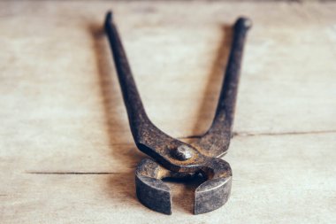 Ahşap arka planda paslı kıskaçlar. Bir şeyleri kavramak ve çekmek için bir araç